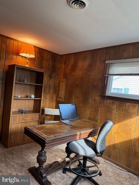 office space with wood walls and carpet flooring