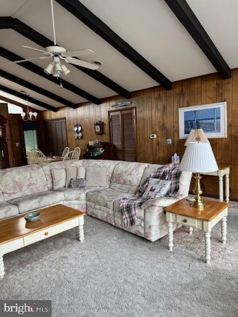 living room featuring lofted ceiling with beams, carpet floors, ceiling fan with notable chandelier, and wood walls