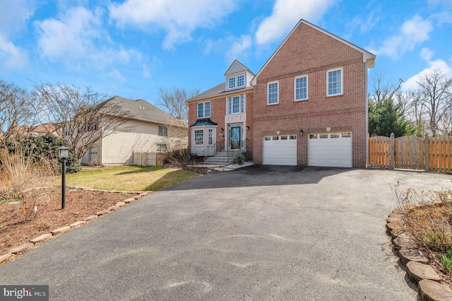 view of front facade featuring driveway, a gate, fence, a garage, and brick siding