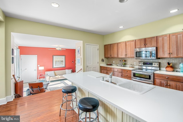 kitchen featuring stainless steel appliances, sink, backsplash, and a kitchen breakfast bar