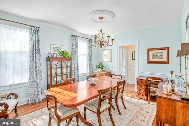 dining room with crown molding, a notable chandelier, and light hardwood / wood-style flooring