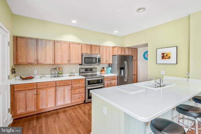 kitchen featuring stainless steel appliances, tasteful backsplash, sink, and a breakfast bar area