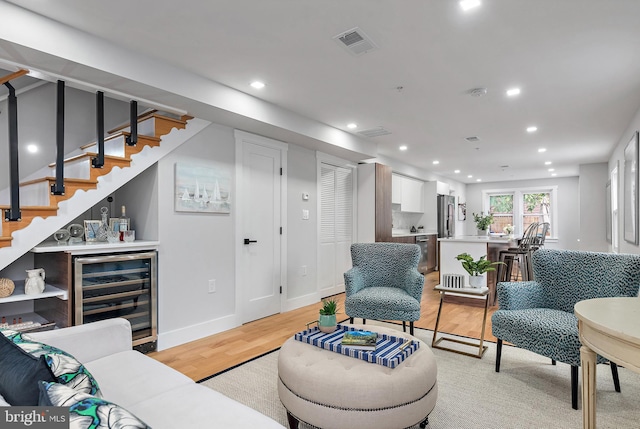 living room with indoor bar, beverage cooler, and light hardwood / wood-style floors