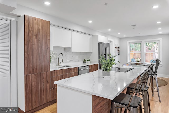 kitchen with sink, a kitchen breakfast bar, a kitchen island, stainless steel appliances, and white cabinets