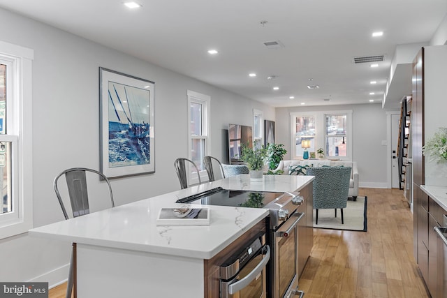 kitchen with stainless steel appliances, a center island, and light hardwood / wood-style floors