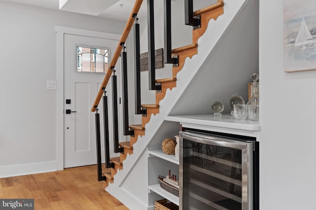 foyer entrance with light hardwood / wood-style floors and beverage cooler