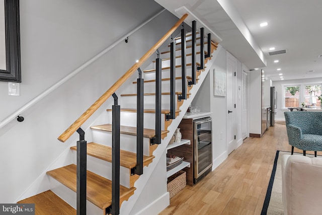 stairway with hardwood / wood-style flooring and wine cooler