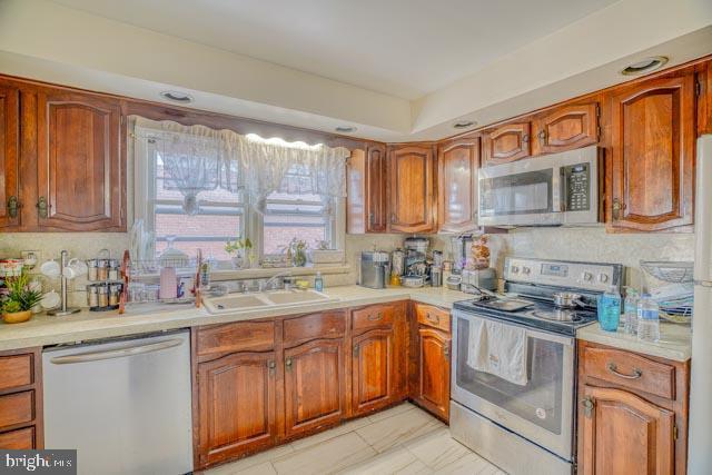 kitchen featuring stainless steel appliances, a sink, and light countertops