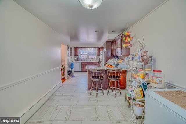 kitchen featuring light countertops, freestanding refrigerator, dishwasher, a peninsula, and a kitchen breakfast bar