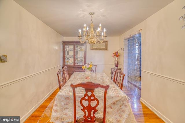 dining room featuring a chandelier, baseboards, and wood finished floors