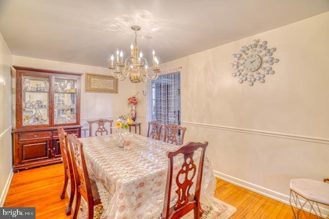 dining room featuring light wood-style flooring, baseboards, and a notable chandelier