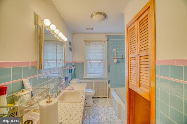 bathroom featuring radiator, crown molding, toilet, and tile walls