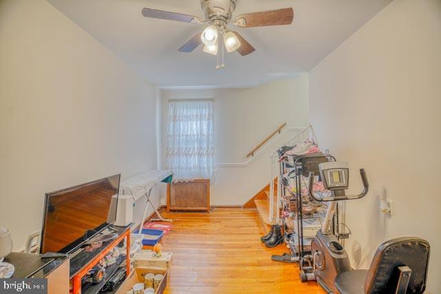 playroom featuring wood finished floors, a ceiling fan, and radiator