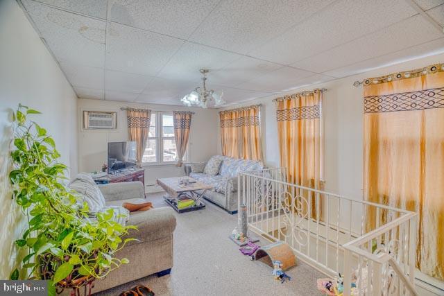 living room with a chandelier, a paneled ceiling, and carpet