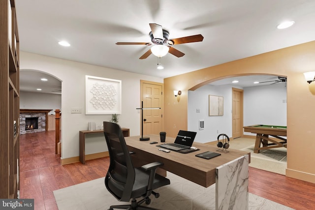 office space with ceiling fan, a fireplace, hardwood / wood-style floors, and billiards