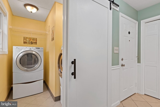 laundry area featuring light tile patterned flooring, a barn door, and separate washer and dryer