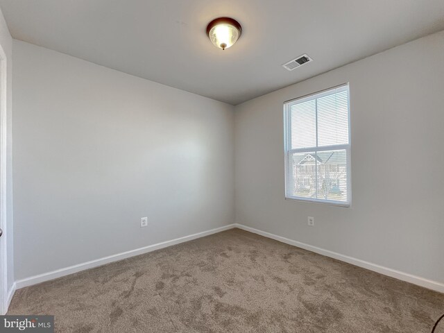 empty room featuring carpet floors, baseboards, and visible vents