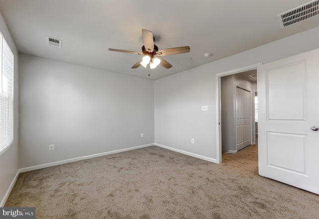 unfurnished room with a ceiling fan, carpet flooring, visible vents, and baseboards