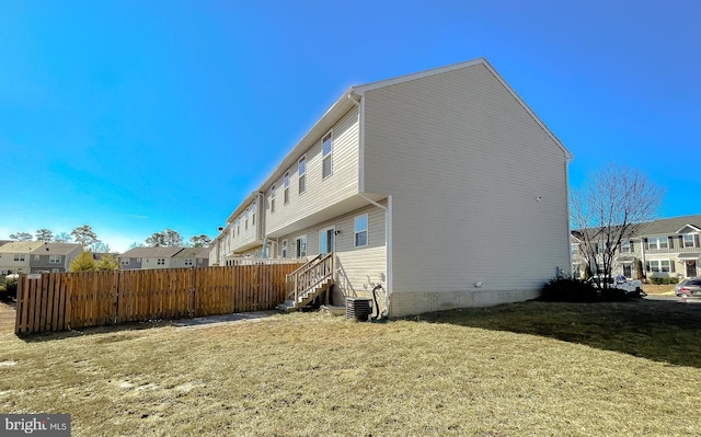 view of side of home featuring a yard, central air condition unit, entry steps, fence, and a residential view