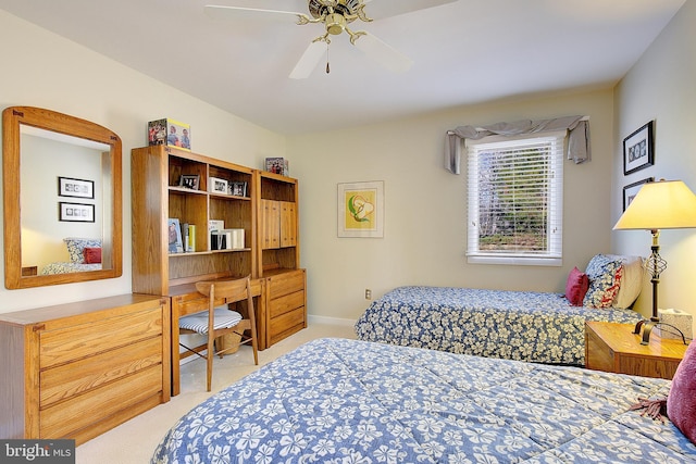 bedroom featuring light carpet, built in desk, and ceiling fan