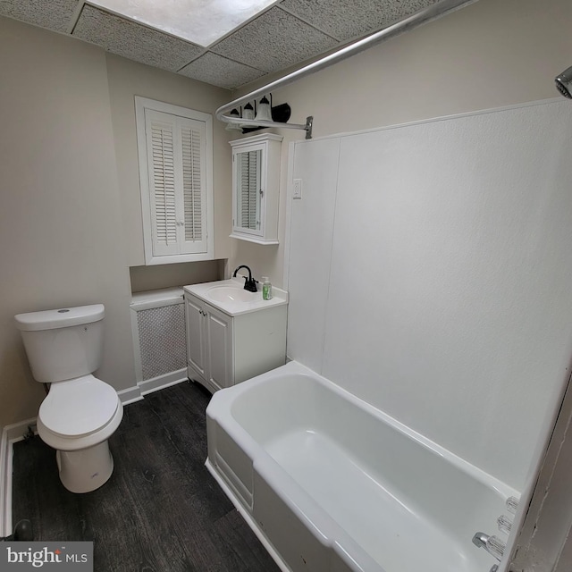 full bathroom featuring toilet, vanity, wood finished floors, a drop ceiling, and baseboards