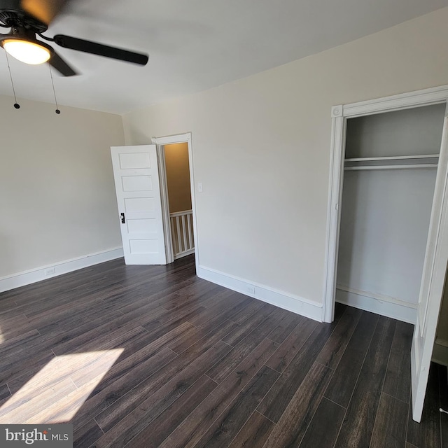 unfurnished bedroom featuring ceiling fan, a closet, baseboards, and dark wood-style flooring