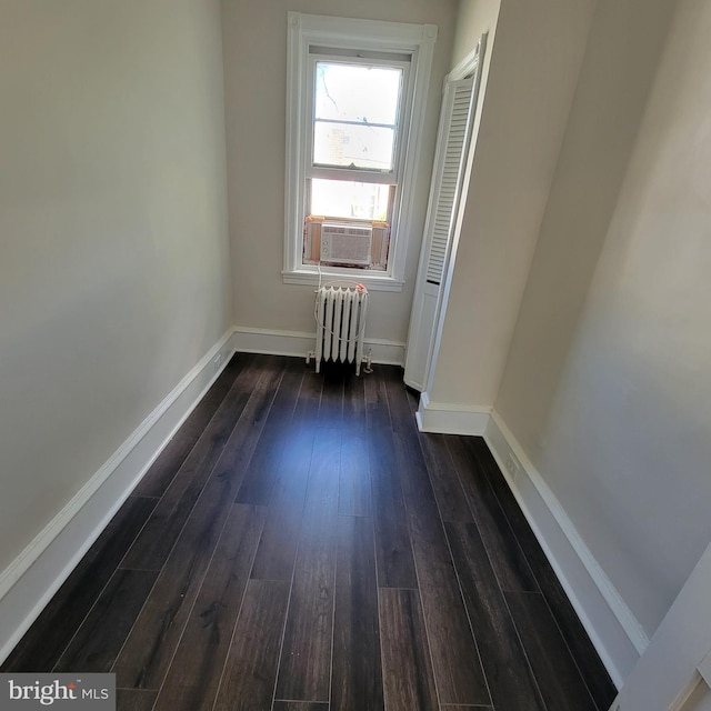 unfurnished room with baseboards, dark wood-style flooring, cooling unit, and radiator