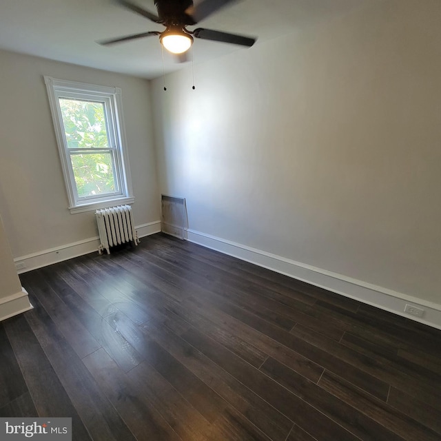 unfurnished room with dark wood-style floors, ceiling fan, baseboards, and radiator