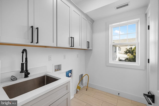 clothes washing area featuring a sink, cabinet space, hookup for a washing machine, visible vents, and baseboards