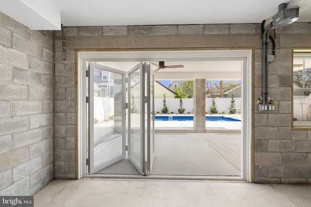 entryway with ceiling fan, concrete block wall, and concrete floors