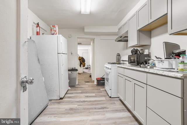 kitchen with sink, white appliances, and light hardwood / wood-style flooring