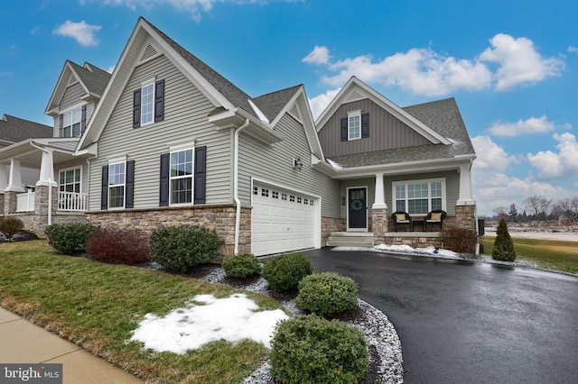 view of front of property featuring board and batten siding, stone siding, covered porch, and driveway