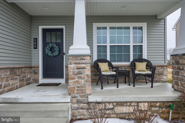 property entrance featuring covered porch and stone siding