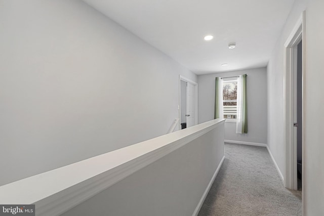 hallway with carpet floors, an upstairs landing, and baseboards