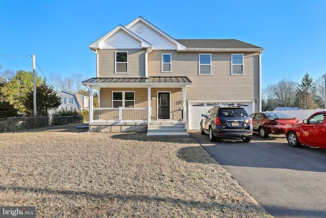 view of front facade with a porch, an attached garage, a standing seam roof, fence, and driveway