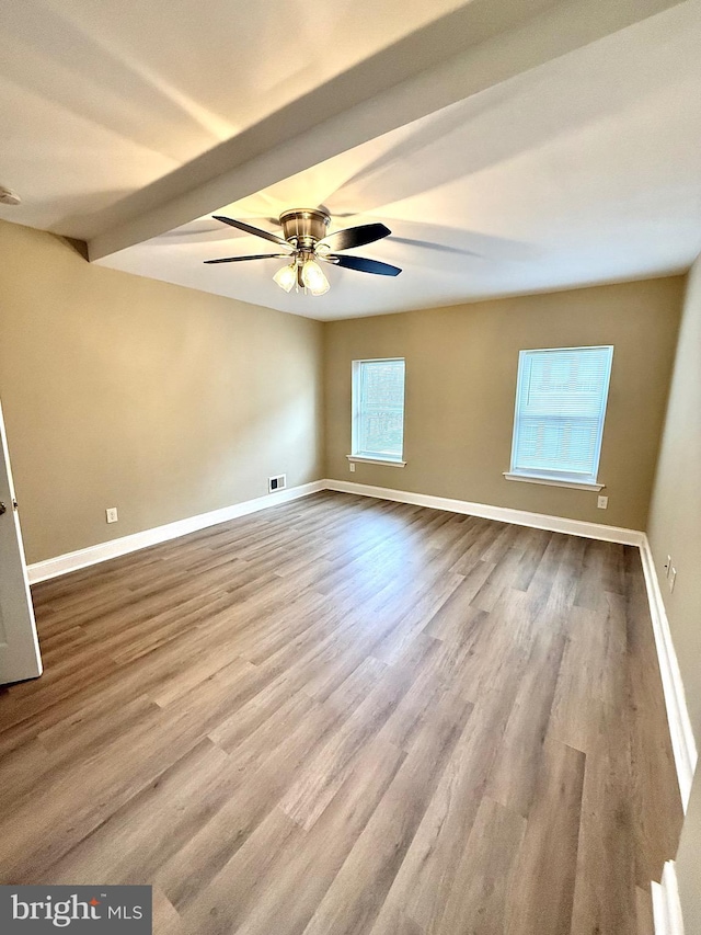 spare room with ceiling fan, light hardwood / wood-style flooring, and beamed ceiling