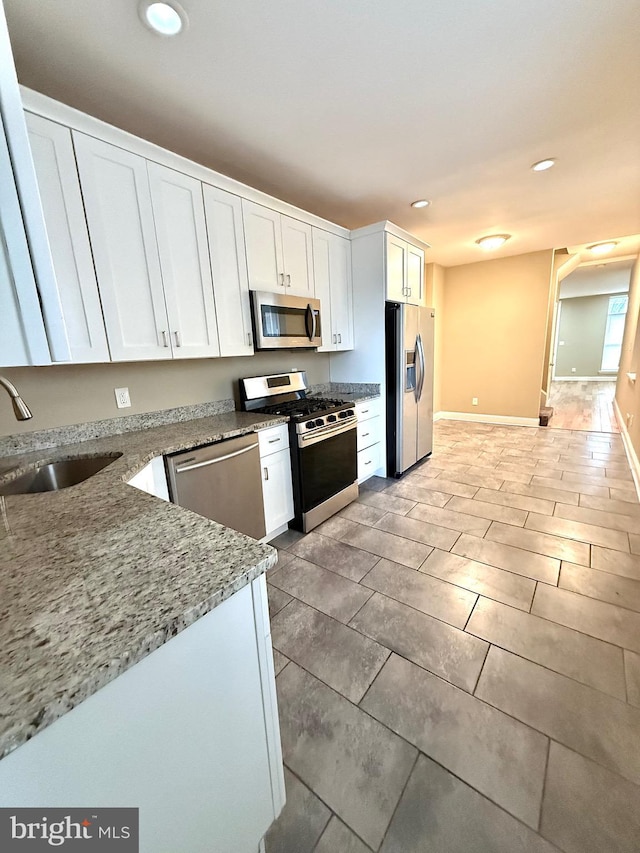 kitchen with white cabinetry, sink, stainless steel appliances, and light stone countertops