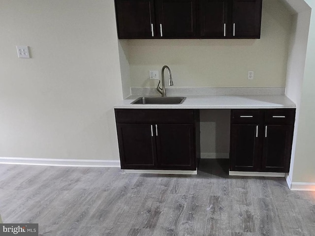 kitchen with dark brown cabinets, sink, and light hardwood / wood-style flooring