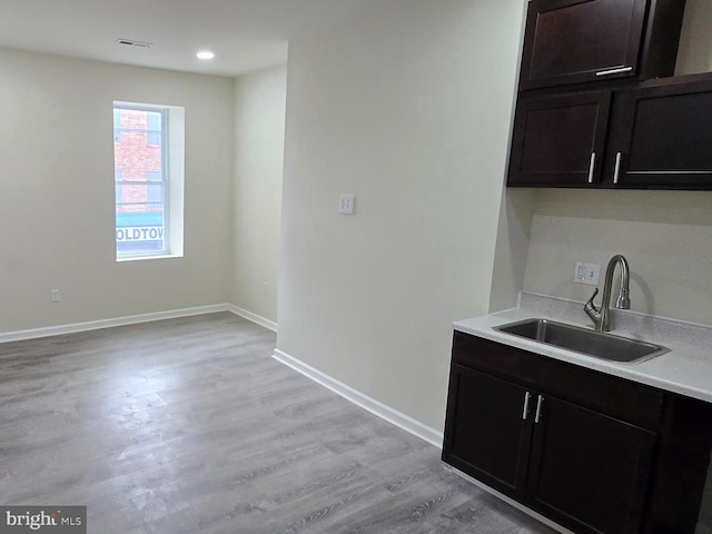 kitchen featuring dark brown cabinetry, sink, and light hardwood / wood-style floors