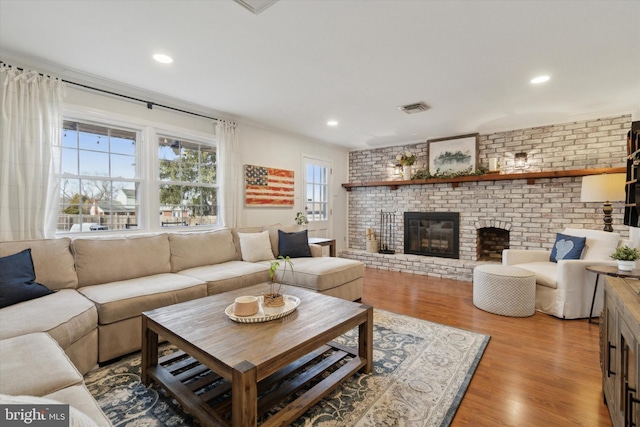 living room featuring a fireplace, brick wall, and light wood-type flooring