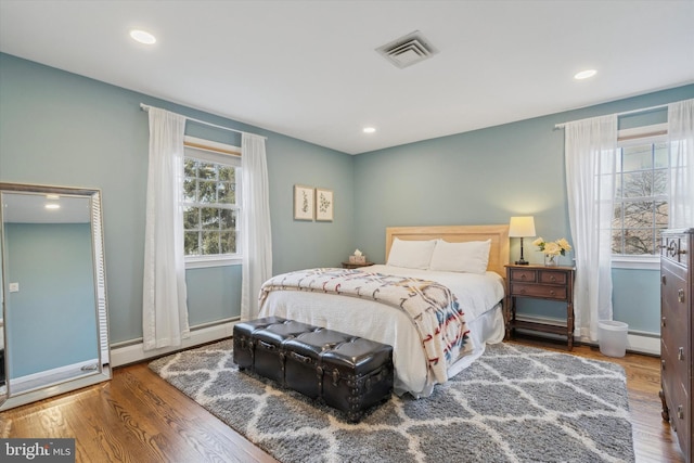 bedroom featuring baseboard heating and wood-type flooring