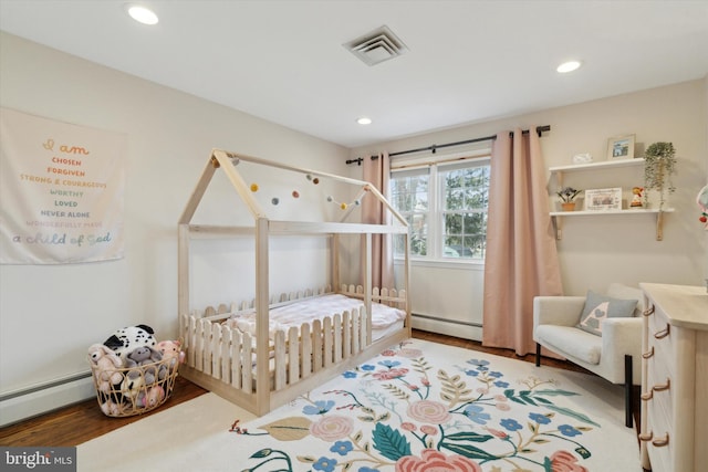 bedroom featuring baseboard heating and wood-type flooring