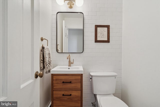 bathroom featuring vanity, tile walls, and toilet