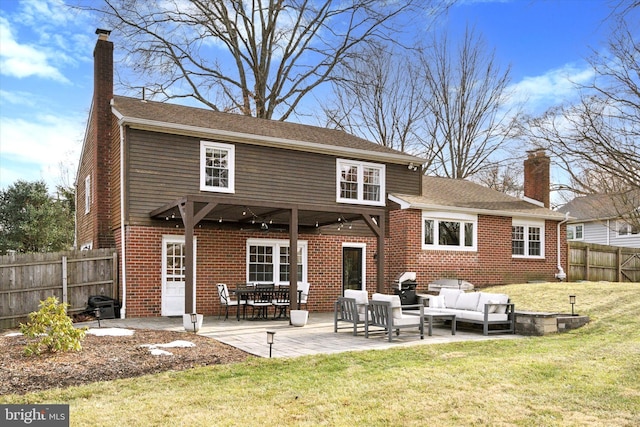 back of house with an outdoor living space, a patio area, and a lawn