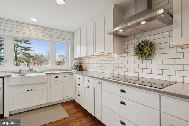 kitchen featuring sink, black electric stovetop, white cabinets, decorative backsplash, and wall chimney exhaust hood