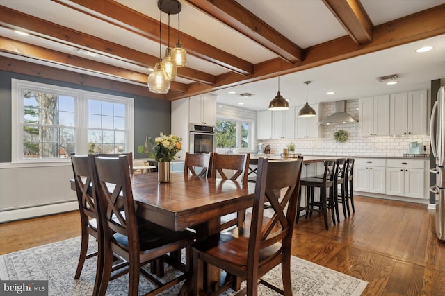 dining room with dark wood-type flooring, baseboard heating, and beamed ceiling