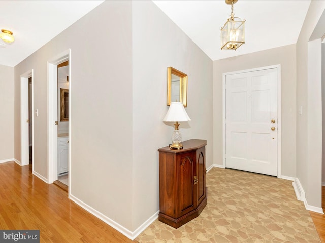 entrance foyer with light wood-type flooring, baseboards, and an inviting chandelier