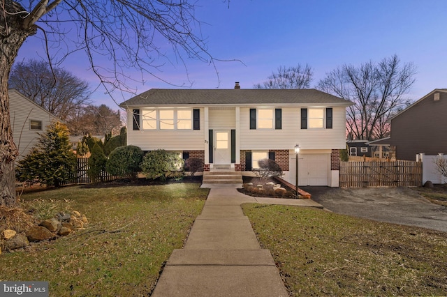 split foyer home featuring a garage and a yard