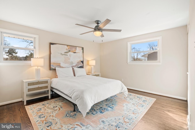 bedroom with multiple windows, wood-type flooring, and ceiling fan