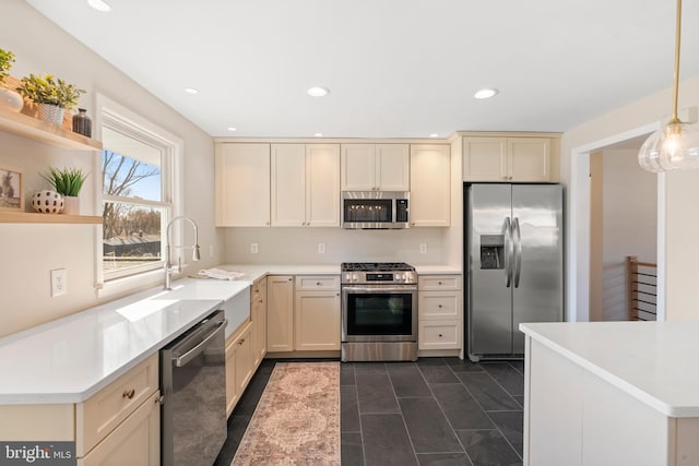 kitchen featuring sink, decorative light fixtures, dark tile patterned floors, stainless steel appliances, and cream cabinetry